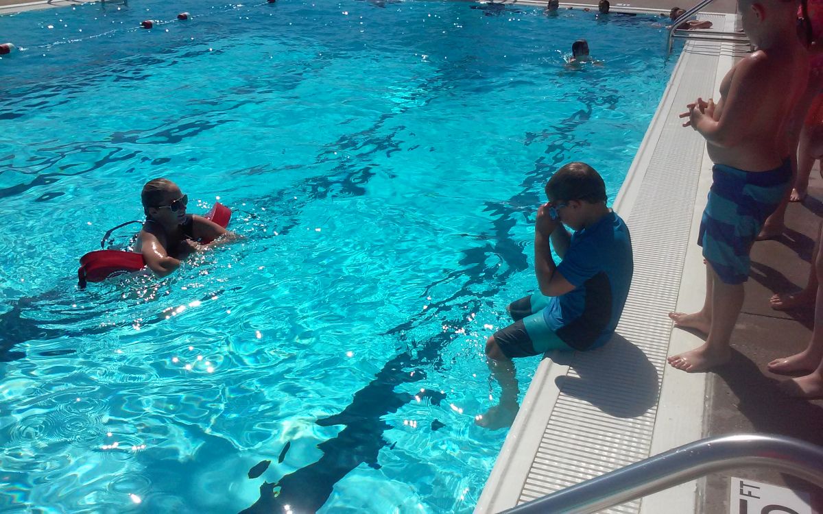 Image of teacher and boy on side of pool